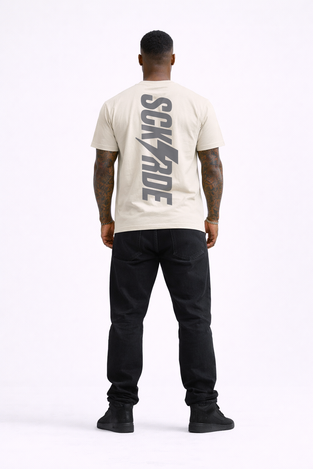 Person wearing a beige t-shirt with 'SCK RIDE' logo on the back, standing against a white background